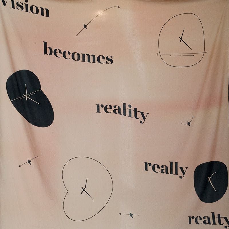 A beige silk print, with the text "Vision becomes reality really realty"
